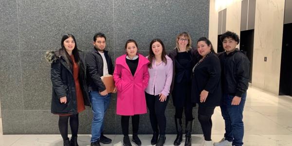 A family poses in front of a gray wall with their NIJC attorneys after their successful hearing