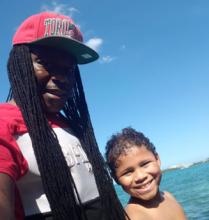 Photo of Kenault and his son, both smiling, with a blue sky behind them