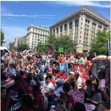 Image of protesters holding signs in front of the Department of Justice in Washington, DC