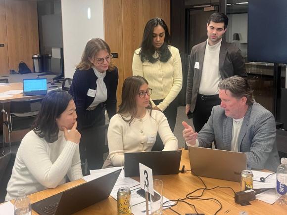 A group of six attorneys from Faegre Drinker gather in a conference room, engaged in a discussion.